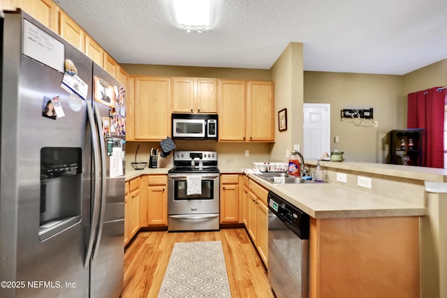 kitchen with light hardwood / wood-style floors, kitchen peninsula, stainless steel appliances, light brown cabinetry, and sink