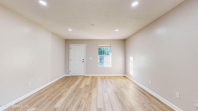 spare room featuring a textured ceiling and light hardwood / wood-style flooring