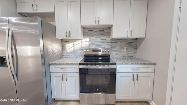 kitchen featuring stainless steel appliances, white cabinets, backsplash, and light stone counters