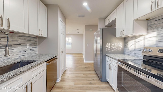 kitchen featuring sink, stainless steel appliances, white cabinetry, and light stone countertops