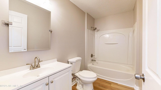 full bathroom featuring a textured ceiling, bathtub / shower combination, hardwood / wood-style floors, toilet, and vanity