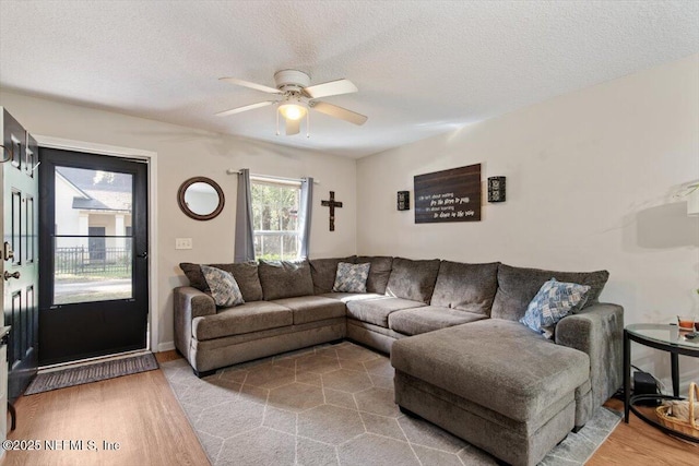 living room featuring ceiling fan, a textured ceiling, and hardwood / wood-style flooring