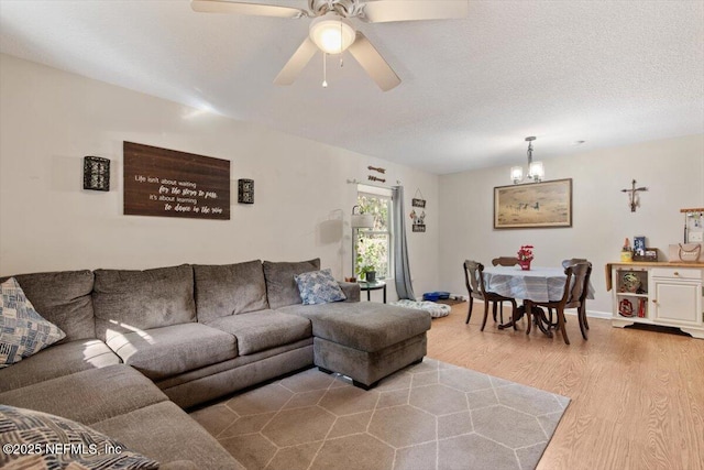 living room with hardwood / wood-style flooring, ceiling fan with notable chandelier, and a textured ceiling