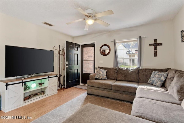 living room with hardwood / wood-style floors, ceiling fan, and a textured ceiling