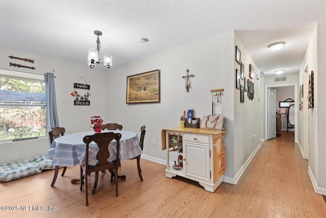 dining room featuring a chandelier, a textured ceiling, and light hardwood / wood-style flooring