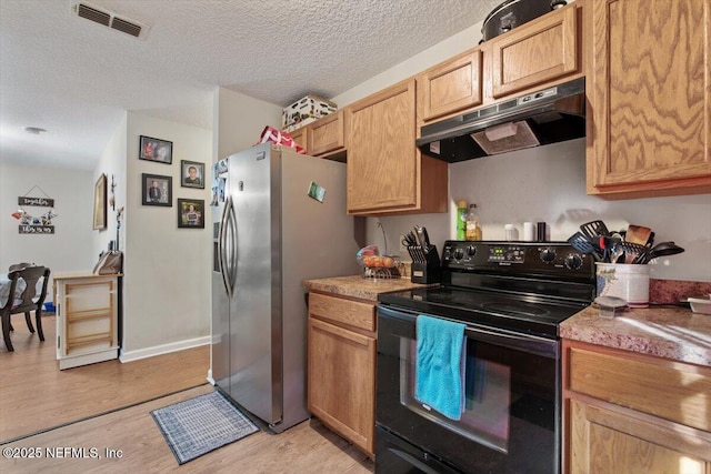 kitchen featuring stainless steel fridge, light wood-type flooring, a textured ceiling, and black / electric stove