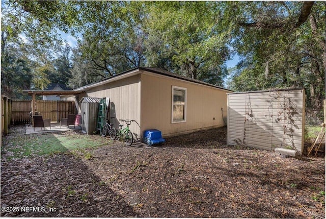 view of property exterior with a patio and a storage unit