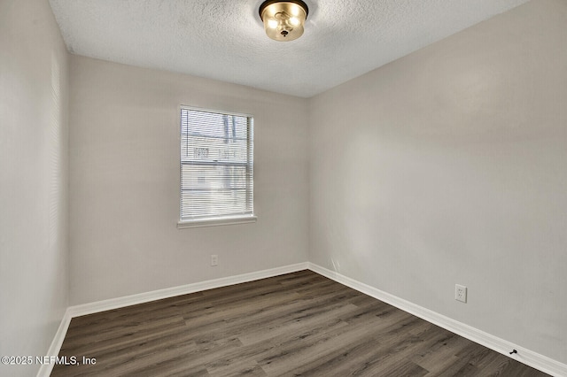 empty room with a textured ceiling and dark hardwood / wood-style floors