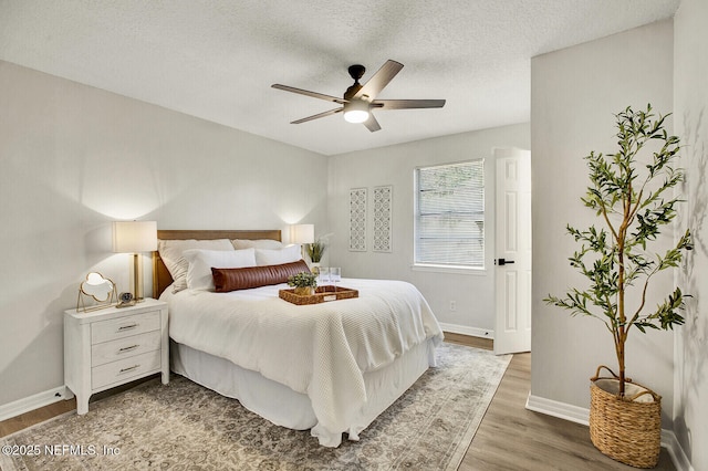 bedroom with ceiling fan, wood-type flooring, and a textured ceiling