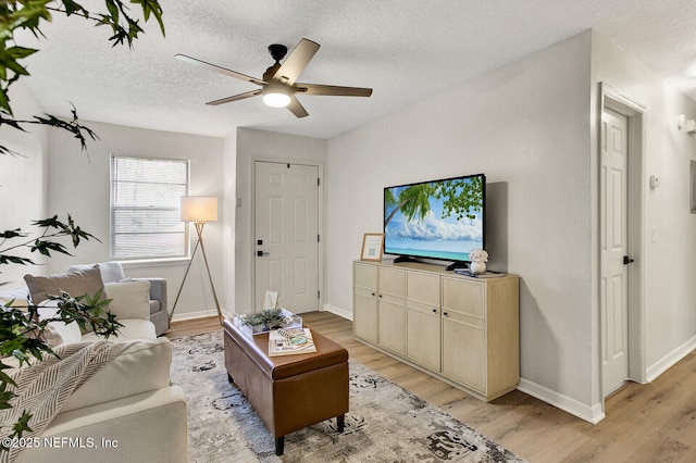 living room featuring ceiling fan, a textured ceiling, and light wood-type flooring