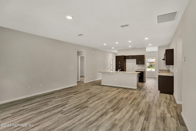 kitchen featuring dark brown cabinetry, a center island with sink, wood-type flooring, and sink