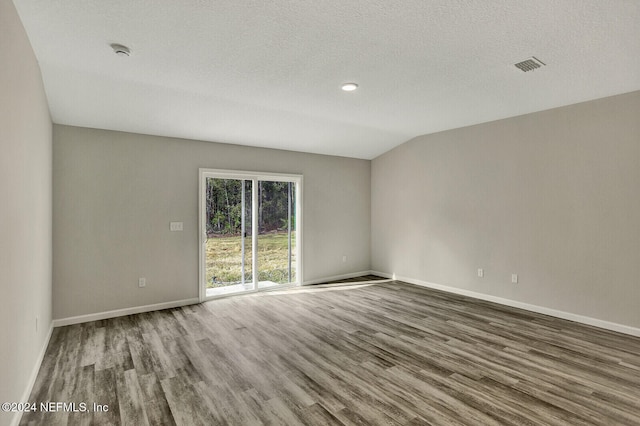 spare room with a textured ceiling, hardwood / wood-style floors, and vaulted ceiling