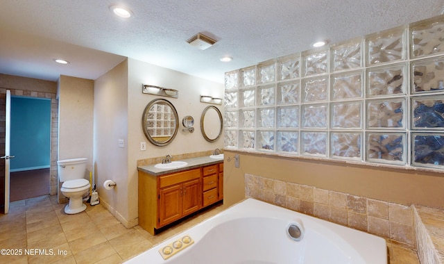 bathroom with tile patterned floors, a washtub, vanity, a textured ceiling, and toilet