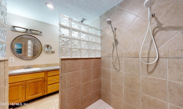 bathroom featuring vanity, tiled shower, and a textured ceiling