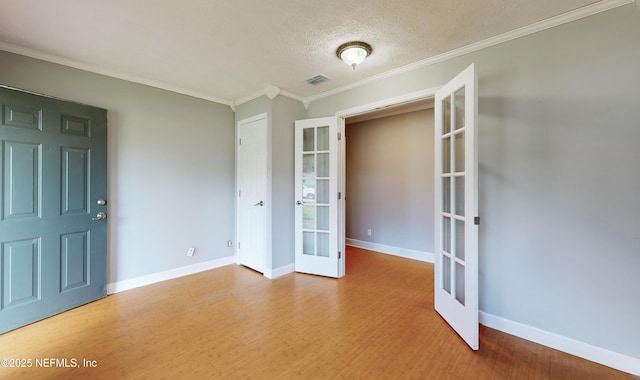 spare room featuring crown molding, french doors, a textured ceiling, and hardwood / wood-style flooring