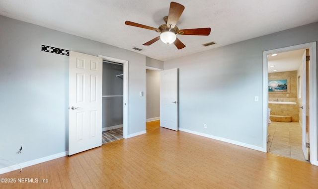 unfurnished bedroom with ceiling fan, light hardwood / wood-style floors, a closet, and ensuite bath