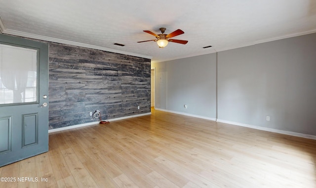 spare room with light wood-type flooring, wooden walls, ceiling fan, and ornamental molding