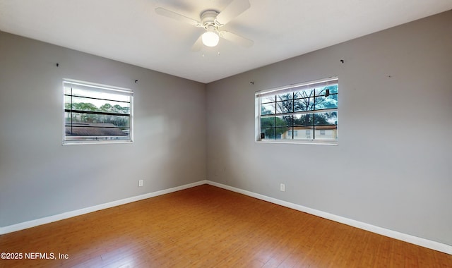 empty room featuring a wealth of natural light, ceiling fan, and wood-type flooring