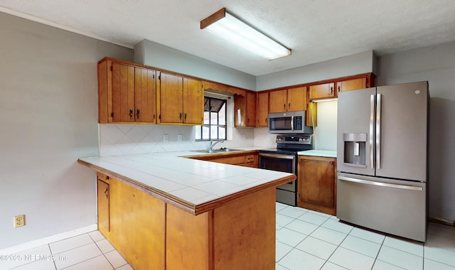 kitchen with sink, tasteful backsplash, kitchen peninsula, light tile patterned floors, and appliances with stainless steel finishes