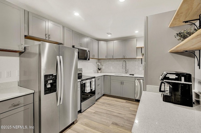 kitchen featuring light wood-type flooring, stainless steel appliances, gray cabinetry, and sink