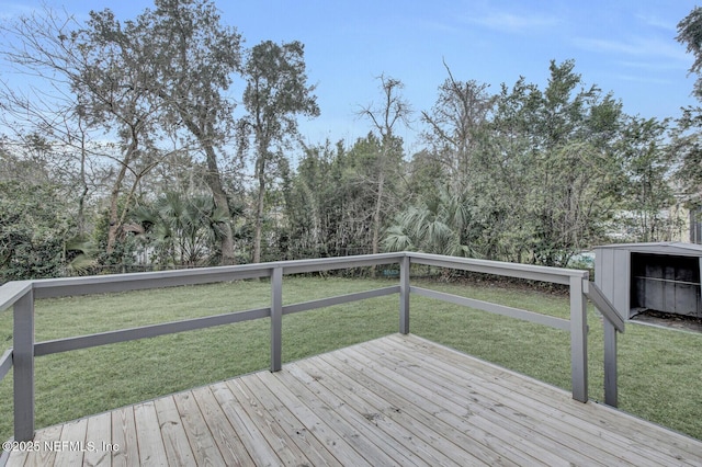 wooden terrace featuring a lawn and a storage unit