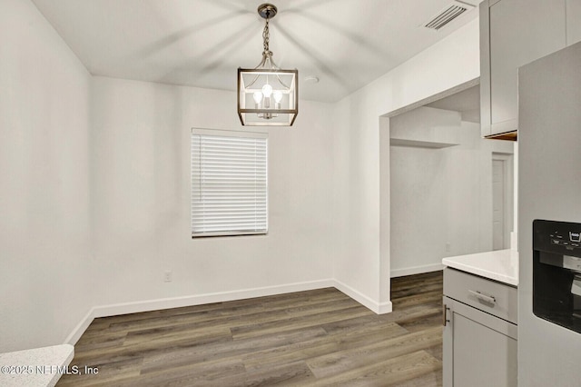 kitchen featuring gray cabinetry, dark wood-type flooring, an inviting chandelier, white fridge with ice dispenser, and decorative light fixtures