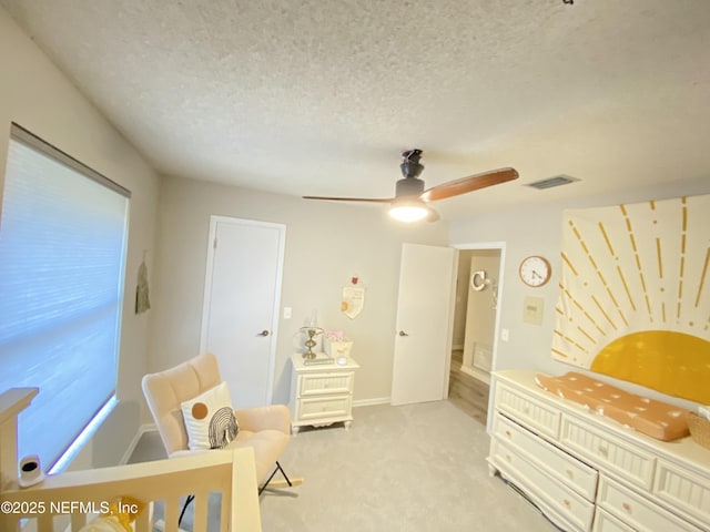 carpeted bedroom featuring ceiling fan and a textured ceiling