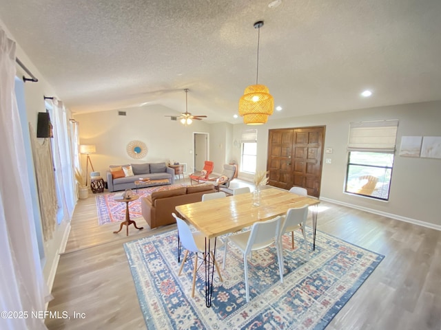 dining space with ceiling fan, a healthy amount of sunlight, lofted ceiling, and light wood-type flooring