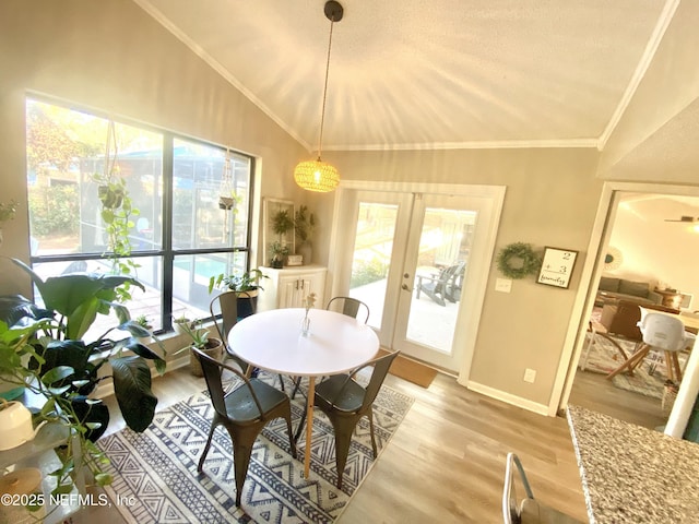 dining area with french doors, light hardwood / wood-style floors, a textured ceiling, vaulted ceiling, and ornamental molding