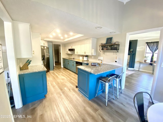 kitchen with blue cabinets, sink, appliances with stainless steel finishes, a tray ceiling, and white cabinetry