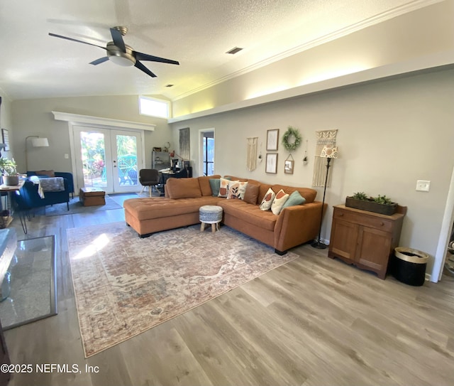 living room with ceiling fan, french doors, a textured ceiling, lofted ceiling, and light wood-type flooring