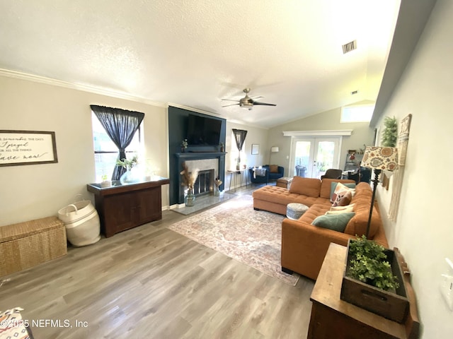 living room with lofted ceiling, french doors, ceiling fan, a textured ceiling, and wood-type flooring