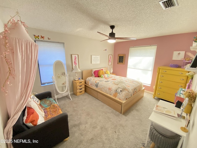 carpeted bedroom featuring ceiling fan and a textured ceiling