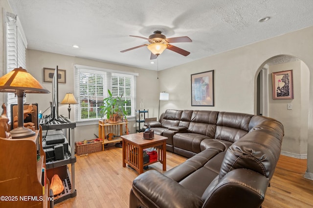 living room featuring a textured ceiling, light wood-type flooring, and ceiling fan