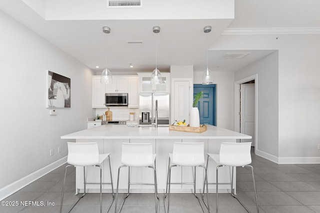 kitchen with a large island, a kitchen breakfast bar, hanging light fixtures, and appliances with stainless steel finishes