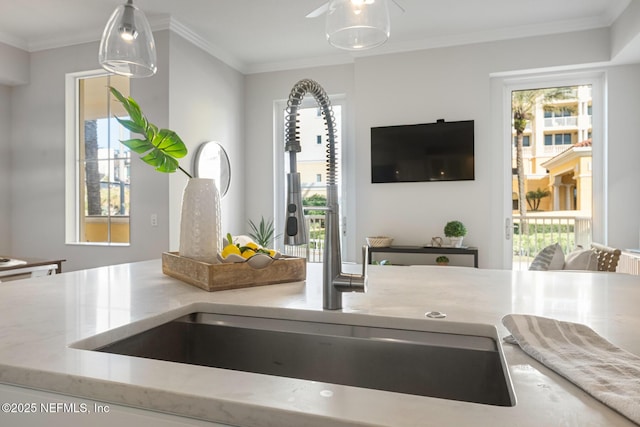 details with light stone countertops, crown molding, sink, and hanging light fixtures