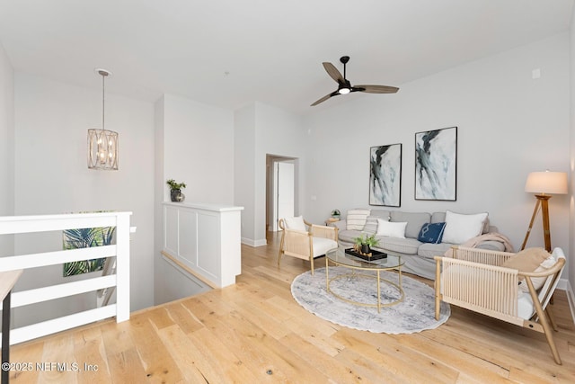 living room with hardwood / wood-style floors and ceiling fan with notable chandelier