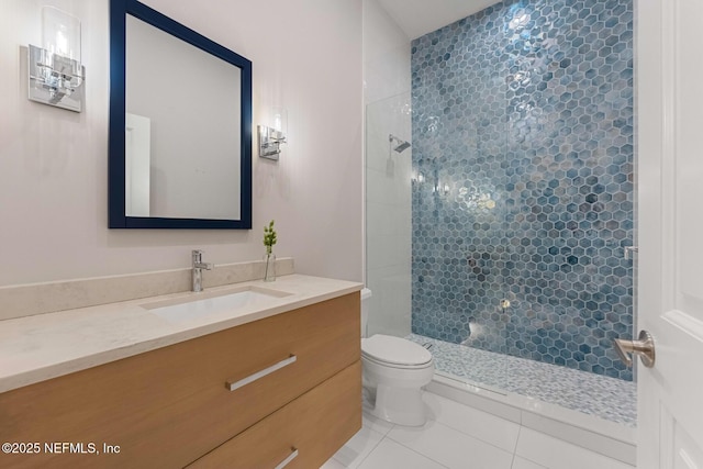 bathroom featuring tile patterned flooring, a tile shower, vanity, and toilet