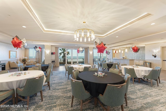 dining area featuring a raised ceiling, crown molding, and a chandelier