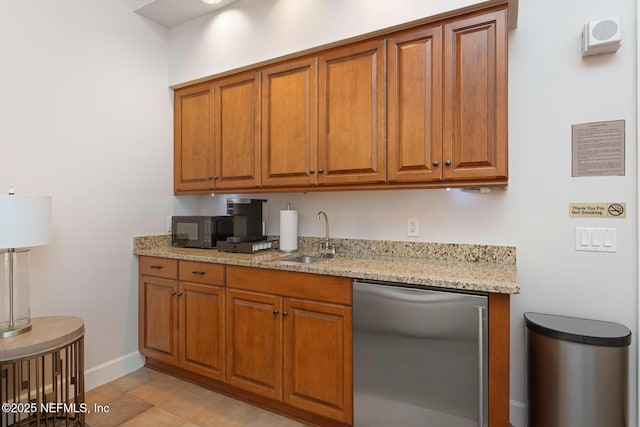 kitchen featuring light stone countertops, sink, and fridge