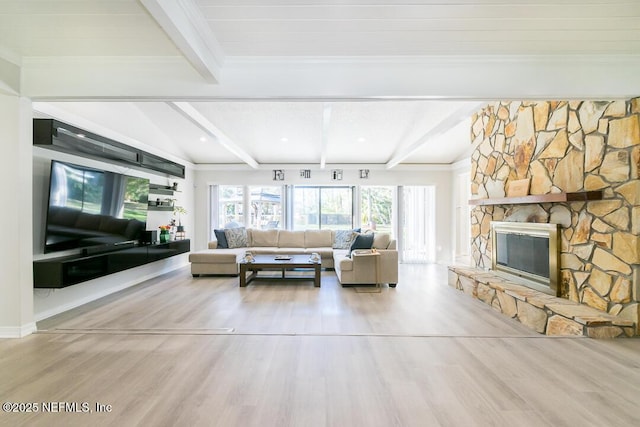 living room featuring hardwood / wood-style floors, lofted ceiling with beams, and a stone fireplace