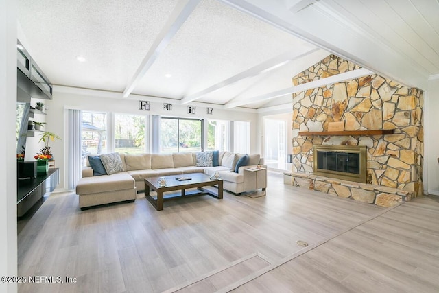 living room with plenty of natural light, a fireplace, a textured ceiling, and light wood-type flooring