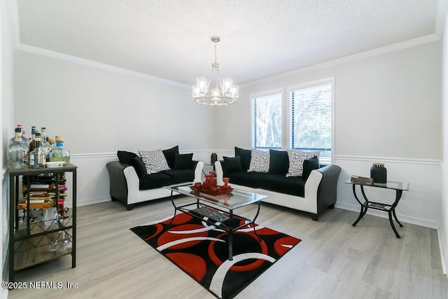 living room with ornamental molding, a chandelier, a textured ceiling, and light hardwood / wood-style floors