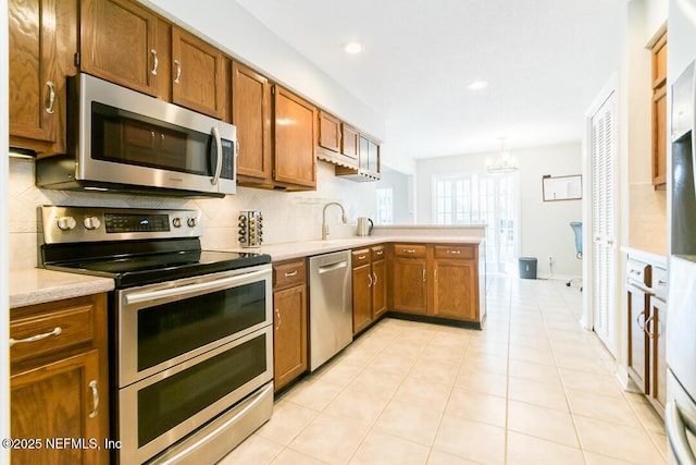 kitchen featuring stainless steel appliances, tasteful backsplash, a chandelier, pendant lighting, and light tile patterned floors