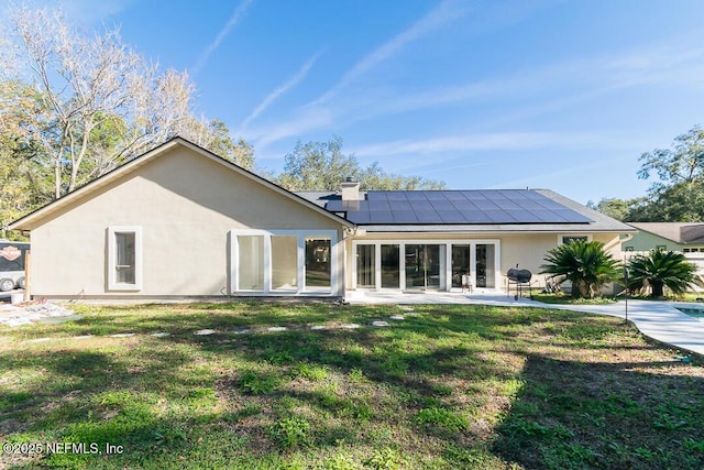 back of house with solar panels, a patio area, and a yard