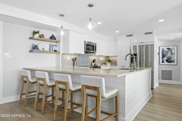 kitchen with kitchen peninsula, appliances with stainless steel finishes, white cabinetry, and sink