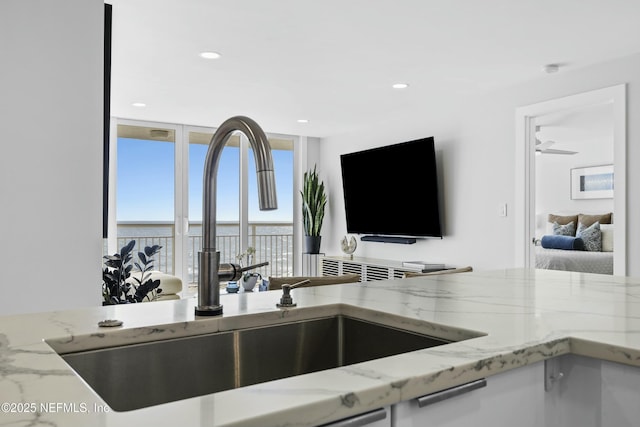 kitchen with light stone countertops, sink, and a wall of windows