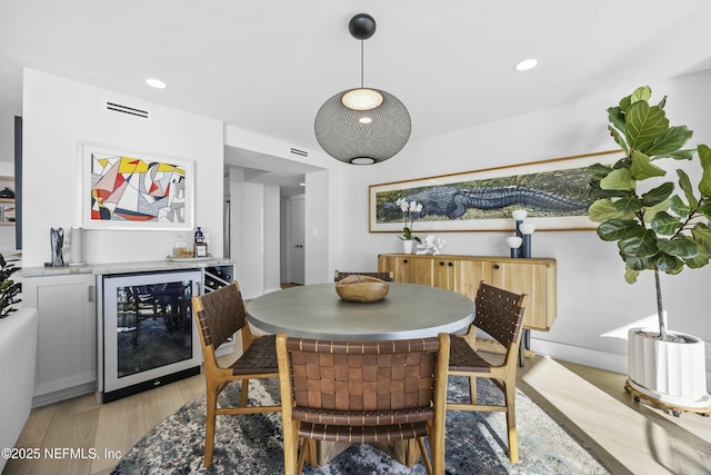 dining room featuring beverage cooler and light hardwood / wood-style floors