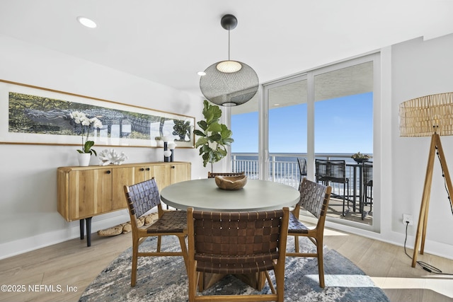 dining room featuring a water view, light hardwood / wood-style flooring, and a wall of windows