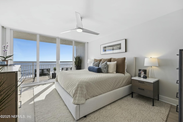 bedroom with access to outside, ceiling fan, a water view, a wall of windows, and light hardwood / wood-style floors